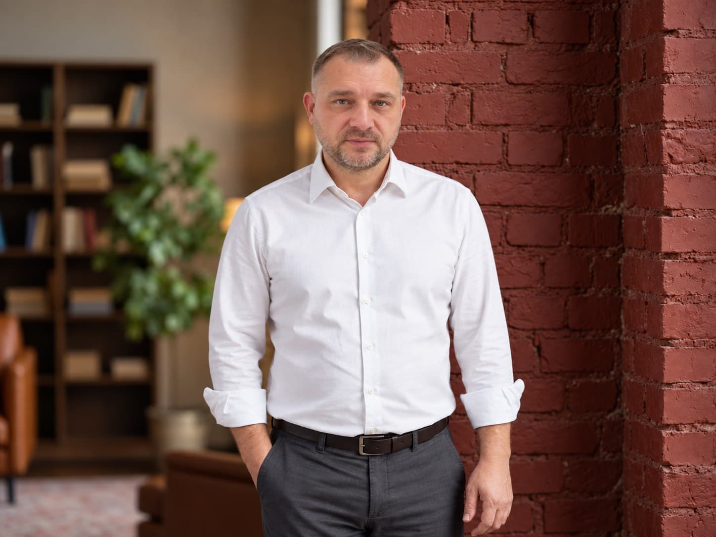 Sebastian Jurkiewicz w białej koszuli przy ceglanej ścianie